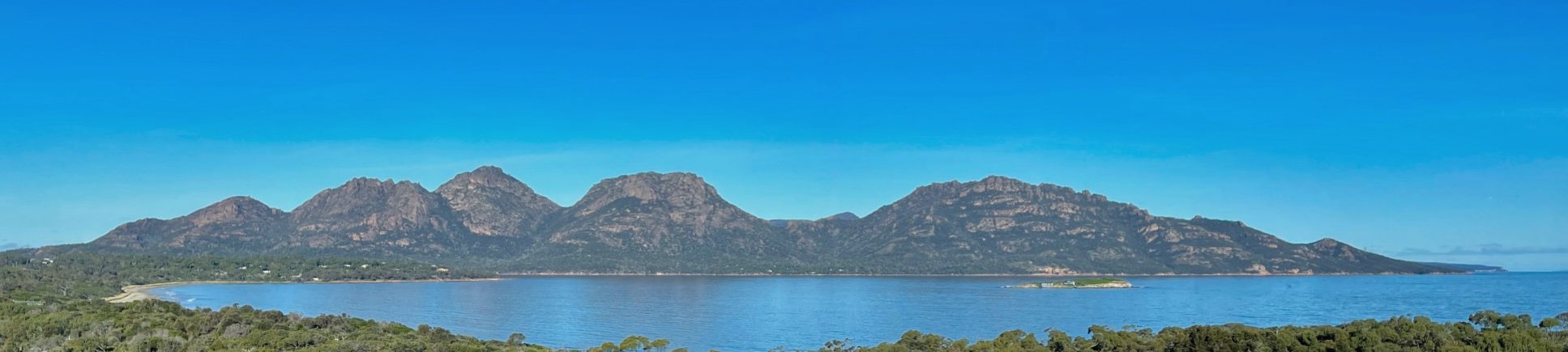 The granite peaks of the Hazards rising above Coles Bay, Freycinet Peninsula, under a clear blue sky